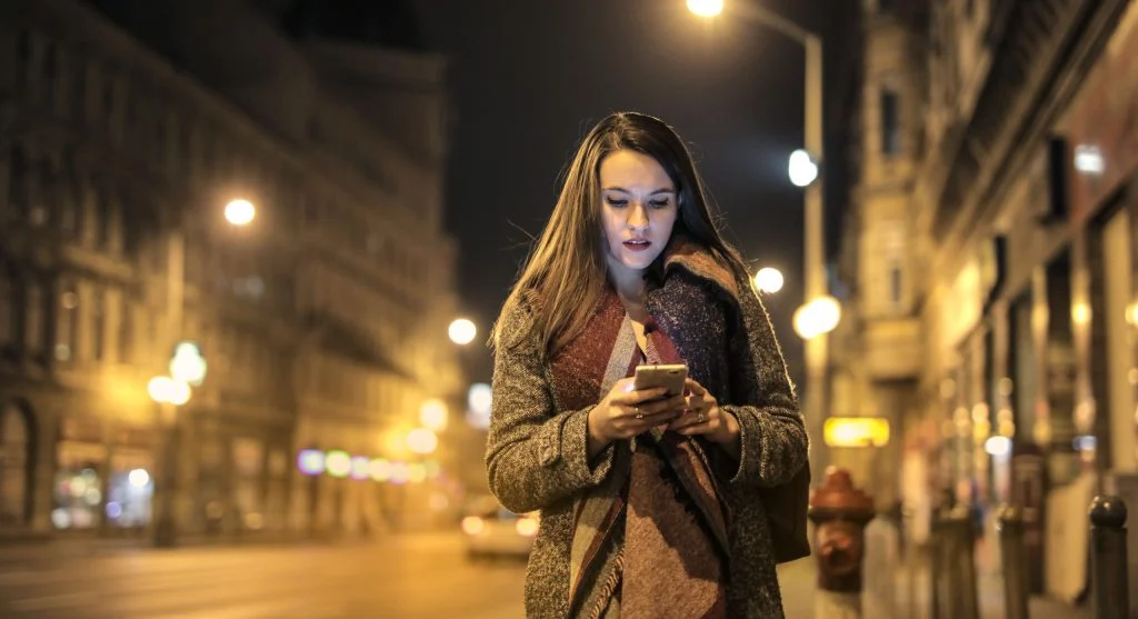 solo traveler checking phone map at night