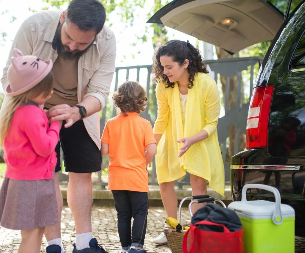 Parents organizing kids' passports, snacks, medicine, and travel bags before departure