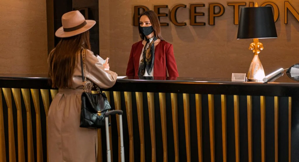 Solo traveler arriving at hotel desk with passport and small bag